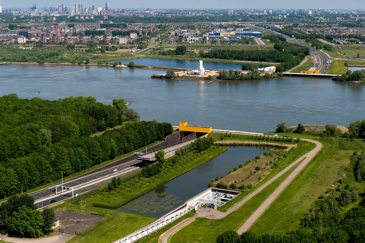 Luchfoto van de Heinenoordtunnel onder de Oude Maas. Op de achtergrond de stad Rotterdam.