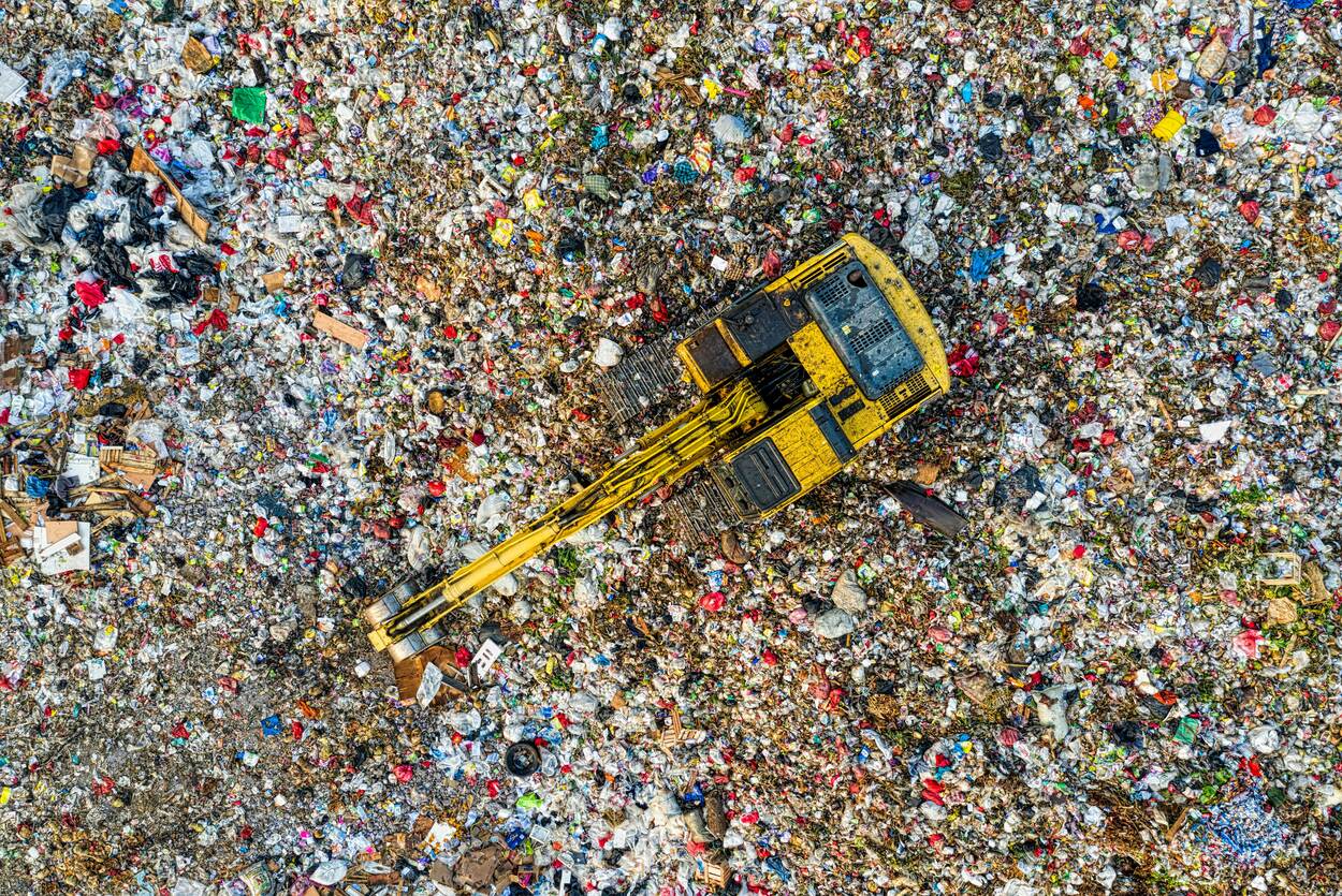 Aerial shot of landfill with a machine on top sorting garbage