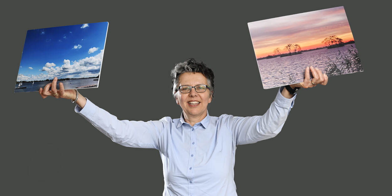 Suzan Orlebeke houdt twee schilderijen in de lucht