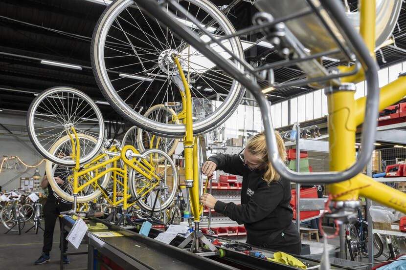 Tussen de fietsen in de werkplaats van Roetz in Amsterdam. Medewerkers met een afstand tot de arbeidsmarkt zijn aan het werk met de gerecyclede fietsen.