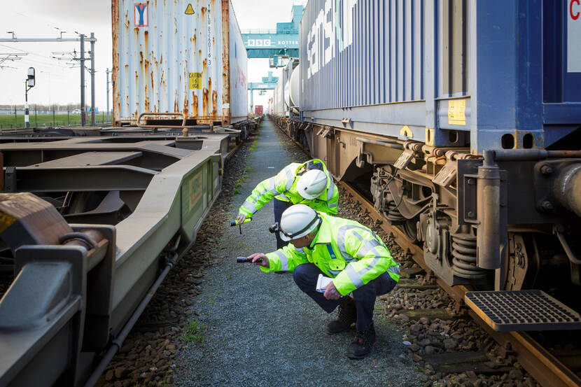 ILT inspecteurs voeren een inspectie uit tussen goederenwagons op het spoor
