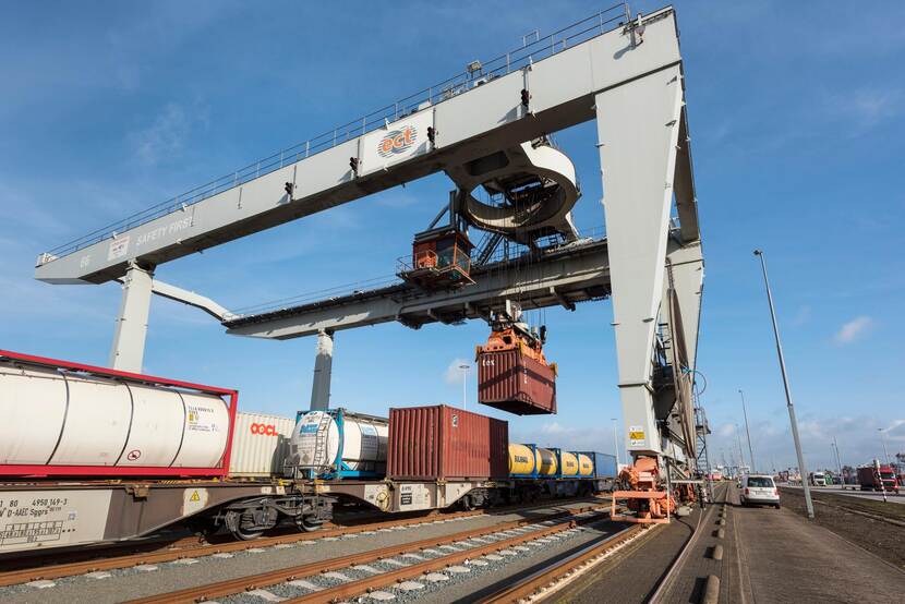 Een grote kraan hijst vrachtcontainers van de ene trein op de andere