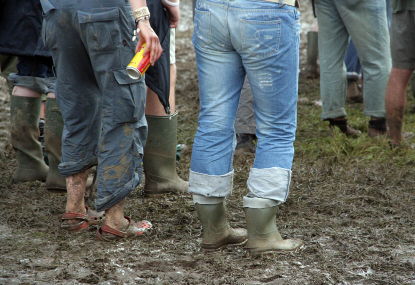 Festivalbezoekers staan met laarzen aan in de modder