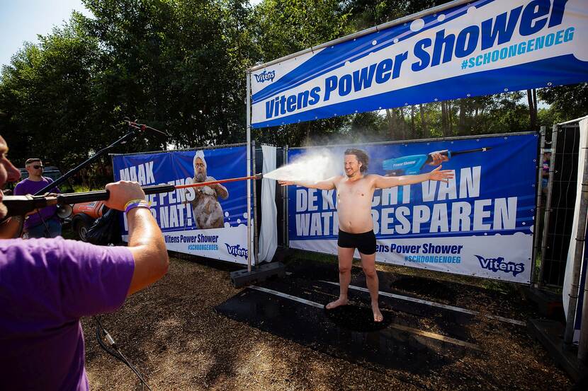 Bezoeker van festival Zwarte Cross maakt gebruik van de power shower: hij wordt schoongespoten met een hogedrukspuit terwijl hij in z'n onderbroek en de armen wijdt staat en de ogen gesloten houdt.