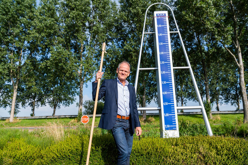 Pieter den Besten naast een NAP-bord op het laagste punt van Nederland
