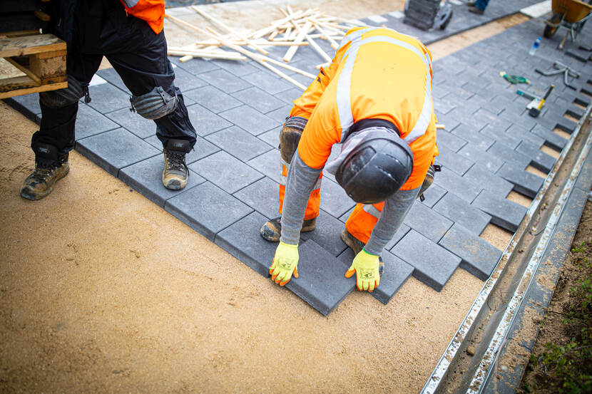 Stratenmaker legt duurzame stoeptegels op het perron van station Bunde