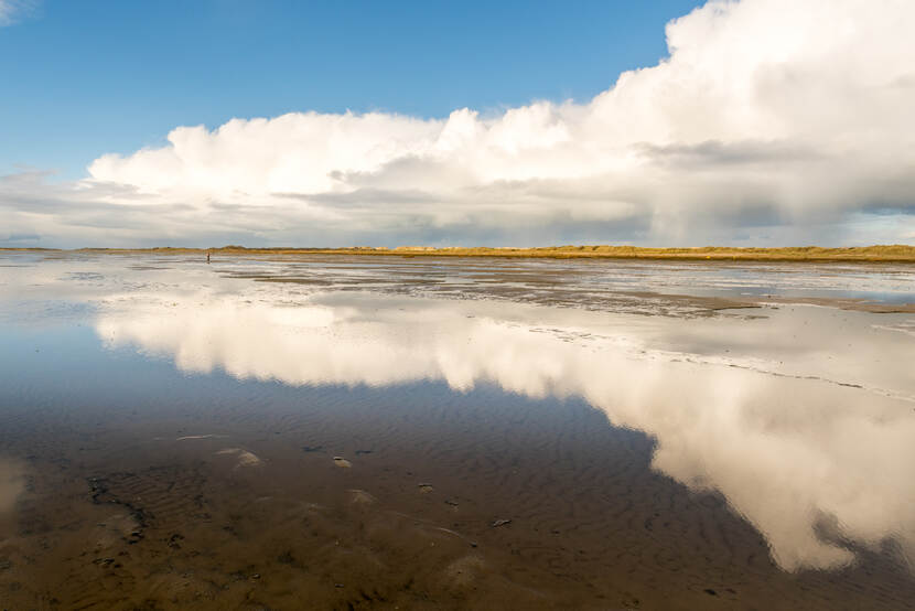 Foto van het water op Terschelling met een bewolkte lucht die weerspiegeld in het water