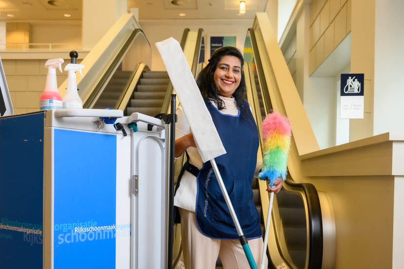 Sharita Dinanath voor de roltrap in de Resident met haar schoonmaakspullen