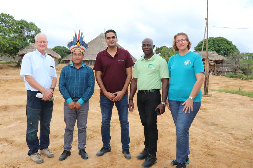 Marc met collega's en een stamhoofd voor een dorpje in het oerwoud