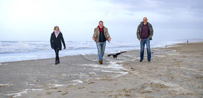 Harry Boschloo, Marieke Buijs en Sybrand Landman lopend op het strand