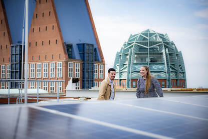Merel Kuiper en Jeroen van Winden op het dak van kantoor Rijnstraat 8 met gebouwen op de achtergrond