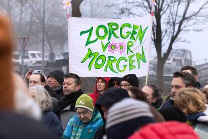 Demonstranten voor de poort van Chemours in Dordrecht dragen een spandoek mee met de tekst Zorgen om morgen