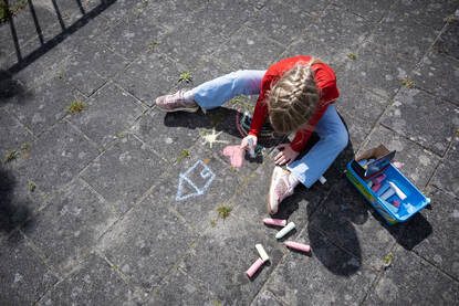Meisje speelt op straat met stoepkrijt