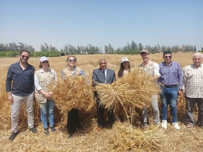 Co-founder & CMO at Chitosan with group of farmers at a field holding two bales of hay
