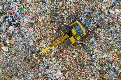 Aerial shot of landfill with a machine on top sorting garbage