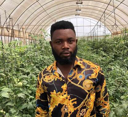 person standing in front of plants in a greenhouse