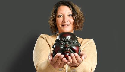 Portretfoto van Charissa Sahadat met een Boedhahoofd in haar handen