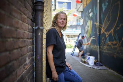 Joy Falkena, een jongerenwerker in een steeg met muurschilderingen