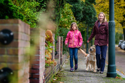 Winnie Teunissen tijdens een wandeling in een groene omgeving samen met haar dochter en hond