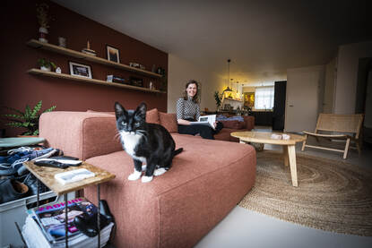 Jet Swart in haar thuiswerkomgeving met op de voorgrond haar zwart met witte kat