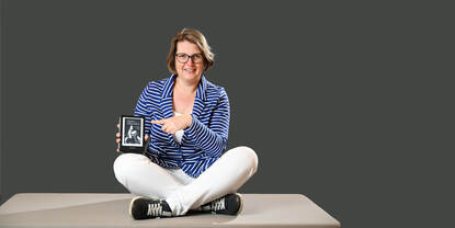 Linda Korpershoek in kleermakerszit met een e-reader in haar handen