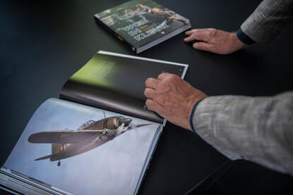 Ad van Liempt bekijkt een ingekleurde foto van een gevechtsvliegtuig