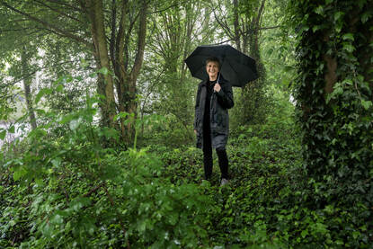 Achrit Wille loopt met een paraplu door een begroeide groene omgeving