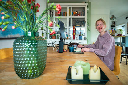 Isa de Beer in haar woonkamer, werkend achter de laptop aan de keukentafel