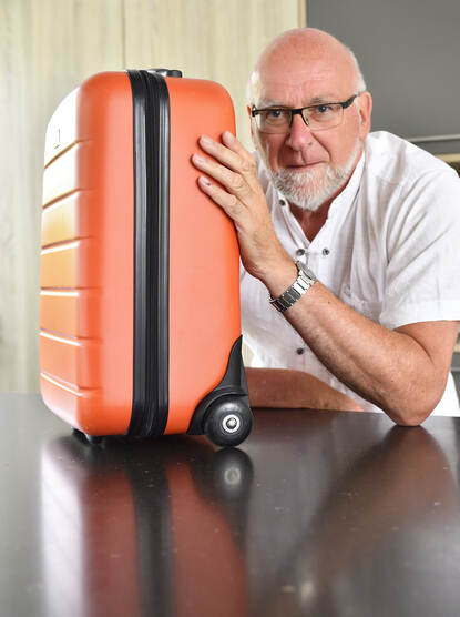 AdVingerhoets met een oranje koffer