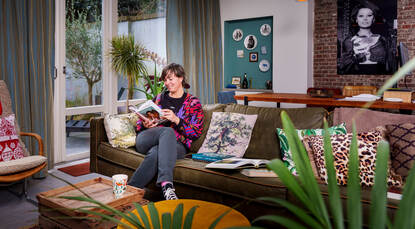 Merijn zit in haar woonkamer op de bank en leest een boek