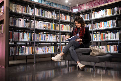 Leonne leest een boek op een bankje in een bibliotheek