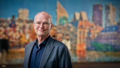 Portret Henk Soorsma met afbeelding van Den Haag op de achtergrond.